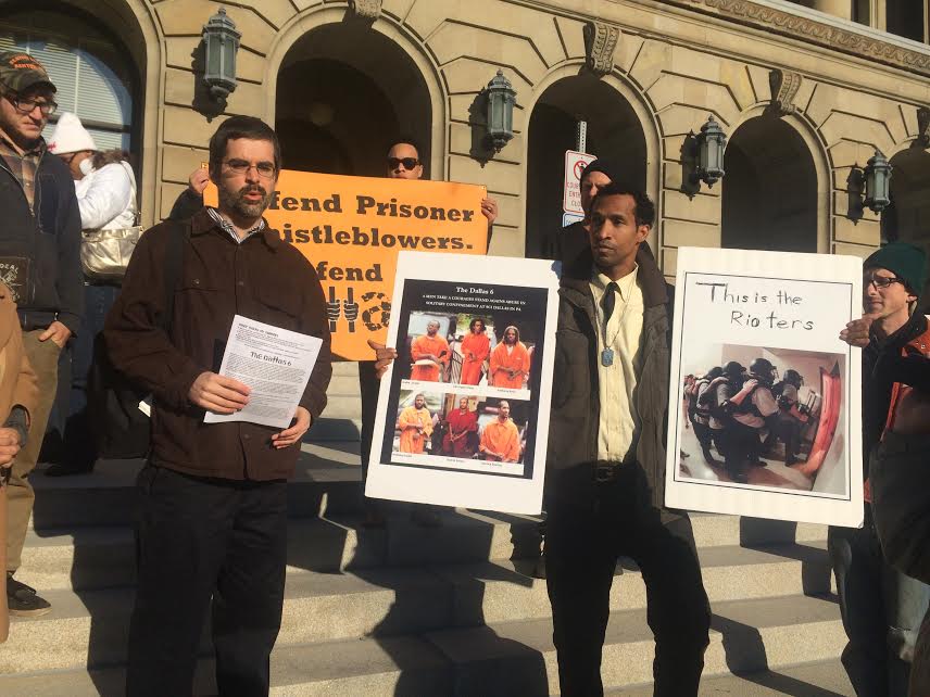 Defendant Derrick Stanley (holding two signs) joins supporters at a press conference outside the courthouse on Monday. Photo: Lynne Iser.
